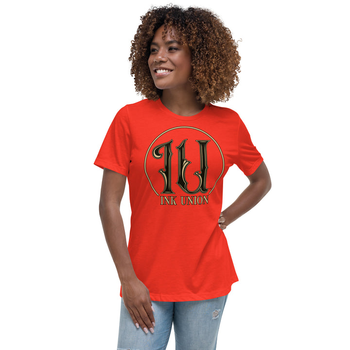 An attractive woman wears a poppy red t-shirt with an Ink Union Circle logo on the chest. The logo is a gold ring with fancy black and gold initials IU in the center.  At the bottom of the circle are the words Ink Union in gold and black.