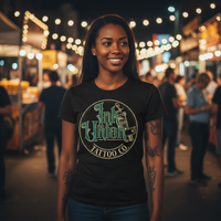 Green & Gold Machine Tee — Tattooed Black female model wearing black Ink Union Tattoo Co. green and gold flash art tattoo machine graphic tee at outdoor night market with colorful food stalls and string lights in background — alternative streetwear, tattoo artist t-shirt, unisex graphic tee, edgy cool fashionMarket