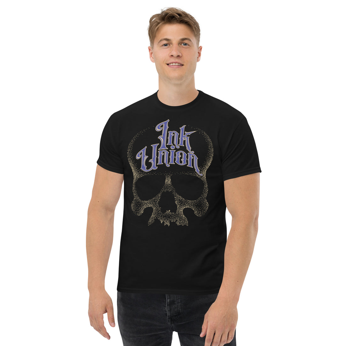 An attractive man wearing a black t-shirt  adorned with a gold dot work human skull and the words Ink Union in fancy gold and blue lettering across the forehead of the skull.