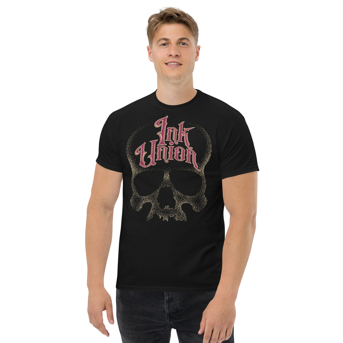 An attractive man wearing a black t-shirt adorned with a gold dot work human skull  and the words Ink Union in fancy gold and red lettering across the forehead of the skull.
