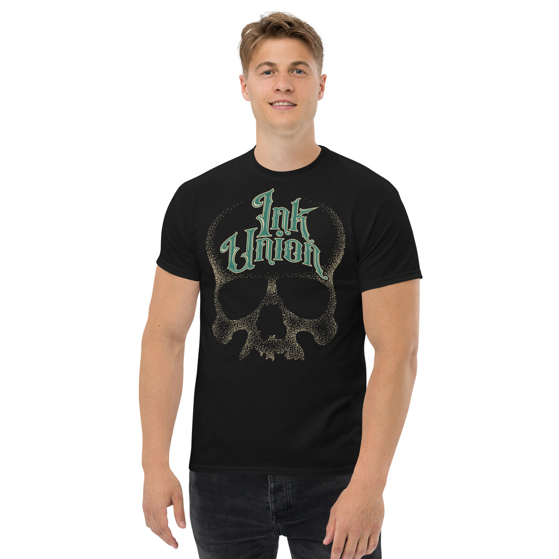An attractive man wearing a black t-shirt  adorned with a gold dot work human skull and the words Ink Union in fancy gold and green lettering across the forehead of the skull.