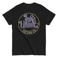 A black t-shirt with a gold circle containing fancy lettering in blue and gold that says Ink Union and a gold tattoo machine peeking out from behind on the right side.  There is a dot work gradient inside the circle, and the words Tattoo Co. in gold are at the bottom of the design.