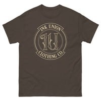 A brown t-shirt adorned with the Ink Union Clothing Co gold badge logo containing fancy lettering and dot work gradients.