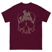 A maroon t-shirt with a gold dot work human skull and the words Ink Union in fancy gold and black lettering across the forehead of the skull.