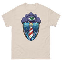 A beige t-shirt with an old school eye of the storm tattoo design of large dark purple storm clouds at the top of the design with a green eye in the middle of the clouds.  Below the clouds is an oval shape with brown rope. Inside the rope are stormy seas and a lighthouse with lightning striking in the background.  At the bottom of the design, some of the waves are spilling out of the rope barrier. The sky and seas are hues of blue; the lighthouse is white and red striped like a barber pole.