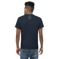 The back view of a man wearing a navy t-shirt with a small gold Ink Union Badge Logo centered just under the neckline.