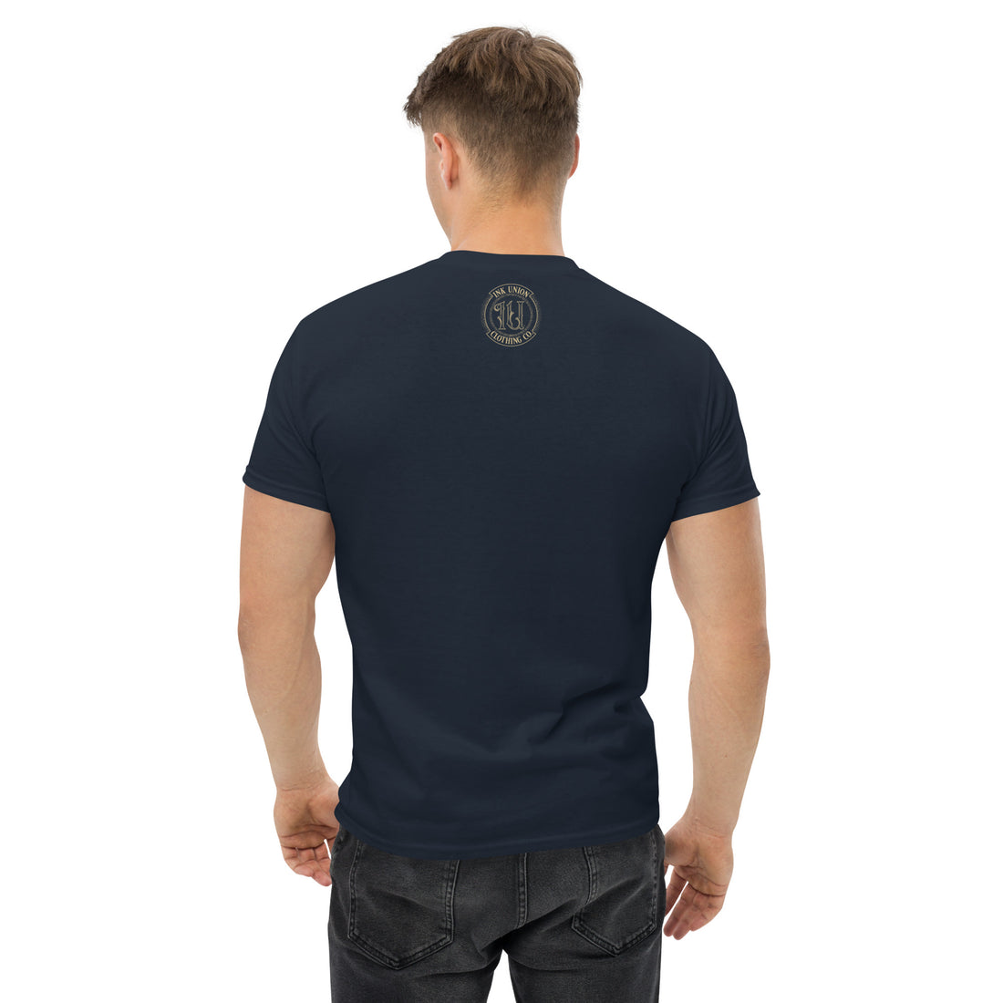 The back view of an attractive man wearing a black t-shirt with a small gold Ink Union Badge Logo centered just under the neckline.