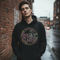 Man wearing black Ink Union Tattoo Co. purple script tattoo machine hoodie on a rainy city street