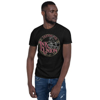 An attractive man wearing a black t-shirt adorned with the Ink Union Tattoo Co. red and gold with a silver tattoo machine logo.