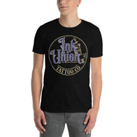 An attractive man wearing a black t-shirt with a gold circle containing fancy lettering in blue and gold that says Ink Union and a gold tattoo machine peeking out from behind on the right side.  There is a dot work gradient inside the circle, and the words Tattoo Co. in gold are at the bottom of the design.