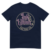 A navy blue t-shirt with a gold circle containing fancy lettering in purple and gold that says Ink Union and a gold tattoo machine peeking out from behind on the right side.  There is a dot work gradient inside the circle, and the words Tattoo Co. in gold are at the bottom of the design.