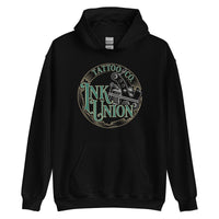 A black hoodie with a gold circle containing fancy lettering in green and gold that says Ink Union and a gold tattoo machine peeking out from behind on the right side.  There is a dot work gradient inside the circle, and the words Tattoo Co. in gold are at the bottom of the design.