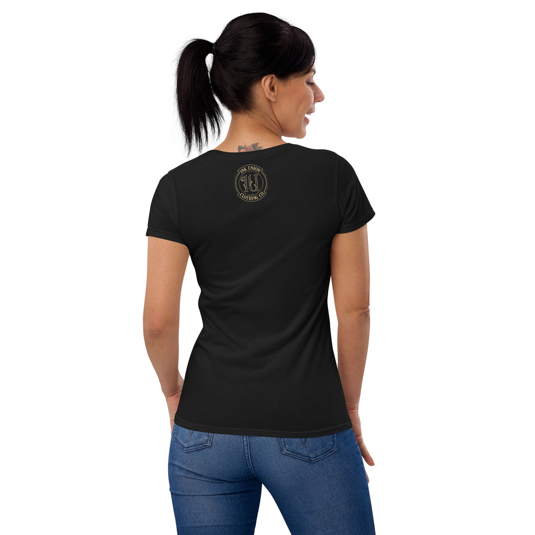 The back view of an attractive woman wearing a black t-shirt with a small gold Ink Union Badge Logo centered just under the neckline.