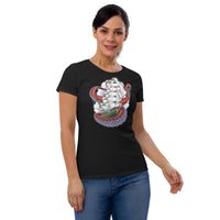 A woman wearing a black T-shirt.  The shirt has an old-school clipper ship tattoo design in green and brown with white sails surrounded by octopus tentacles in shades of red with purple tentacles. Behind the ship are purple-tinged clouds.