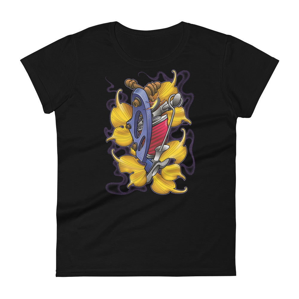 A black t-shirt with a bed of yellow ginkgo leaves and a blue tattoo machine popping out of the leaves. There is a purple mist in the background.