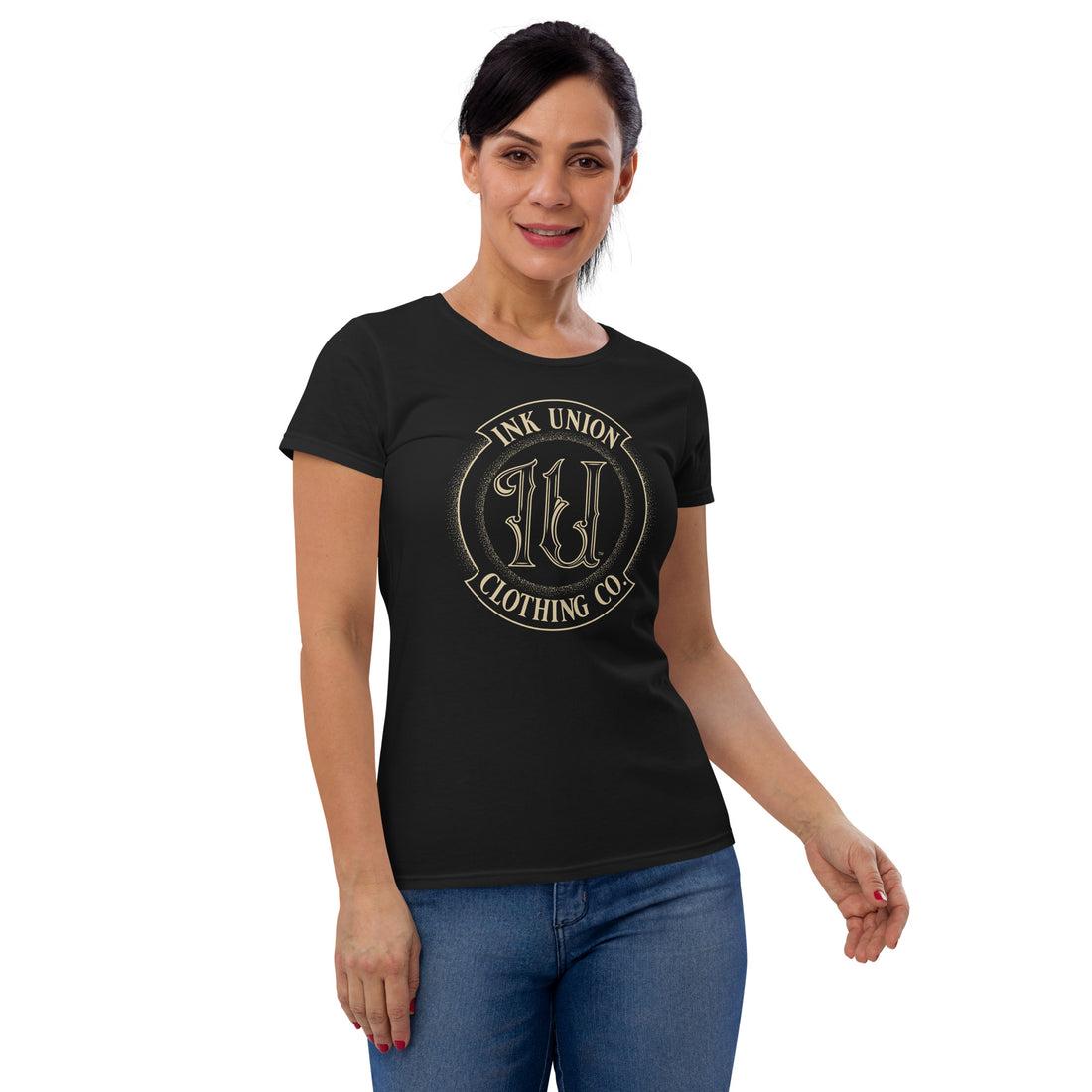 An attractive woman is wearing a black t-shirt adorned with the Ink Union Clothing Co gold badge logo containing fancy lettering and dot work gradients.