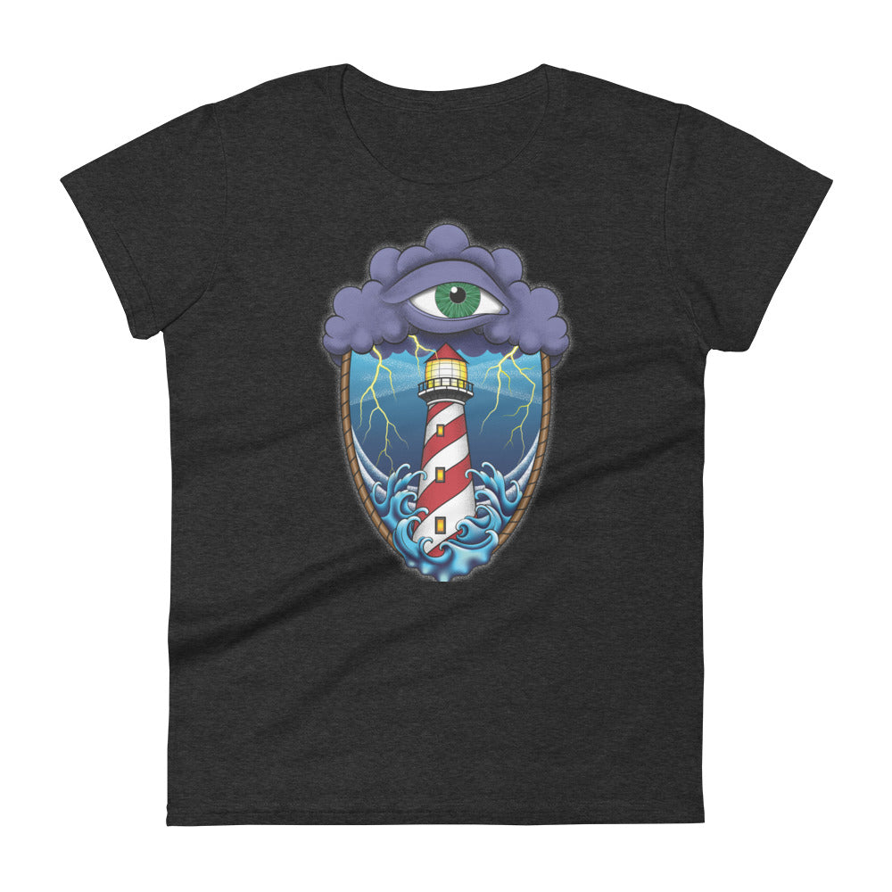A dark grey t-shirt with an old school eye of the storm tattoo design of large dark purple storm clouds at the top of the design with a green eye in the middle of the clouds.  Below the clouds is an oval shape with brown rope. Inside the rope are stormy seas and a lighthouse with lightning striking in the background.  At the bottom of the design, some of the waves are spilling out of the rope barrier. The sky and seas are hues of blue; the lighthouse is white and red striped like a barber pole.