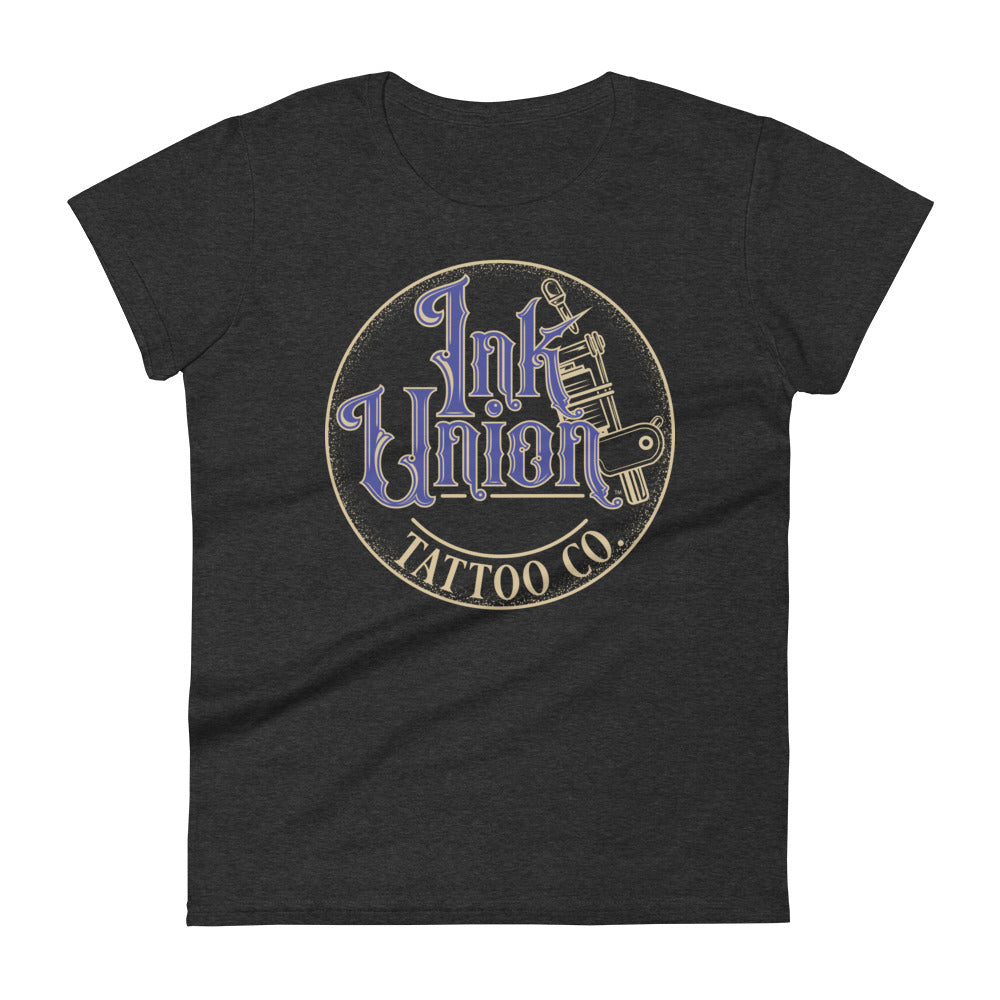 A dark grey t-shirt with a gold circle containing fancy lettering in blue and gold that says Ink Union and a gold tattoo machine peeking out from behind on the right side. There is a dot work gradient inside the circle, and the words Tattoo Co. in gold are at the bottom of the design.