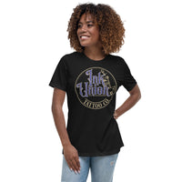 An attractive woman wearing a black t-shirt with a gold circle containing fancy lettering in blue and gold that says Ink Union and a gold tattoo machine peeking out from behind on the right side.  There is a dot work gradient inside the circle, and the words Tattoo Co. in gold are at the bottom of the design.