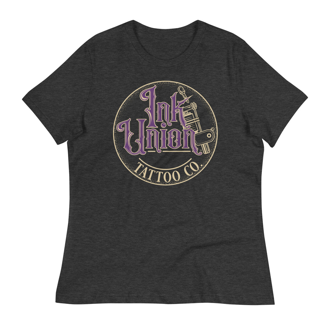 A dark grey t-shirt with a gold circle containing fancy lettering in purple and gold that says Ink Union and a gold tattoo machine peeking out from behind on the right side. There is a dot work gradient inside the circle, and the words Tattoo Co. in gold are at the bottom of the design.