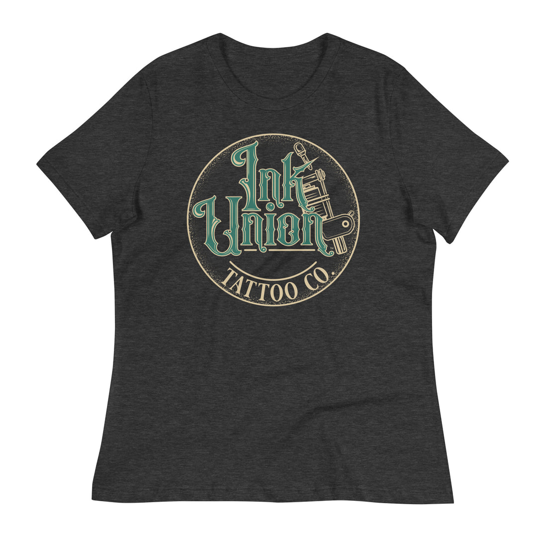 A dark grey t-shirt with a gold circle containing fancy lettering in green and gold that says Ink Union and a gold tattoo machine peeking out from behind on the right side. There is a dot work gradient inside the circle, and the words Tattoo Co. in gold are at the bottom of the design.