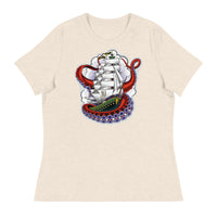 A light brown t-shirt with an old-school clipper ship tattoo design in green and brown with white sails surrounded by octopus tentacles in shades of red with purple tentacles. Behind the ship are purple-tinged clouds.