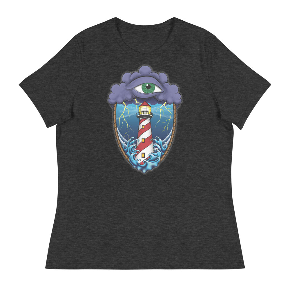 A dark grey t-shirt with an old school eye of the storm tattoo design of large dark purple storm clouds at the top of the design with a green eye in the middle of the clouds.  Below the clouds is an oval shape with brown rope. Inside the rope are stormy seas and lightning striking at a lighthouse that is white and red striped like a barber pole.