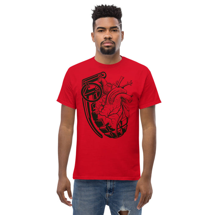 An attractive man is wearing a red t-shirt adorned with a black grenade morphing into an anatomical heart.