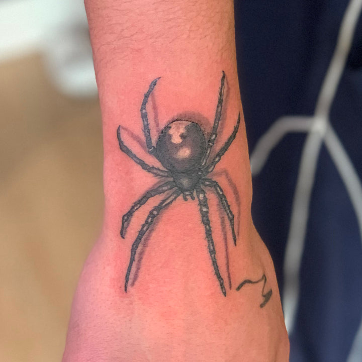 realisitc black and grey spider tattoo on the top of the wrist and hand