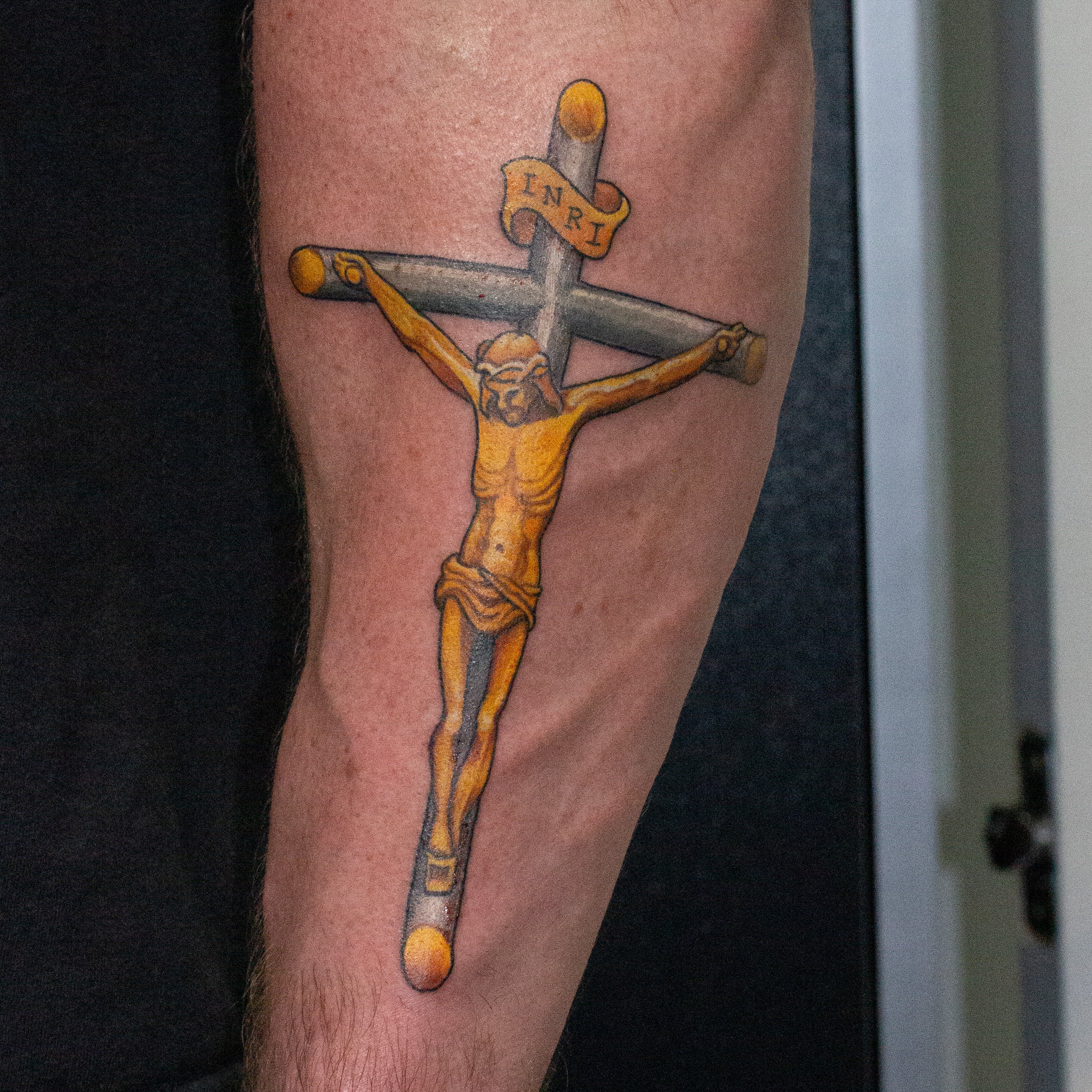 Gold and silver tattoo of a crucifix.