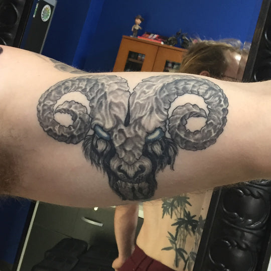 Black and grey tattoo of a demonic rams head.