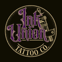 A black background with a gold circle containing fancy lettering in purple and gold that says Ink Union and a gold tattoo machine peeking out from behind on the right side.  There is a dot work gradient inside the circle, and the words Tattoo Co. in gold are at the bottom of the design.