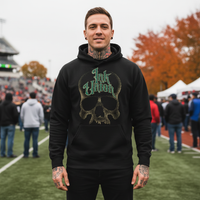 Green & Gold Dot Work Skull Hoodie — Tattooed male model wearing black Ink Union Tattoo Co. green and gold dot work skull hoodie at outdoor fall sporting event with autumn foliage in background — alternative streetwear, tattoo artist sweatshirt, unisex heavy blend hoodie, edgy cool fashion

