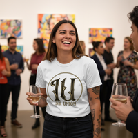 Ink Union Circle Logo Tee — Tattooed Hispanic female model wearing white Ink Union Tattoo Co. IU circle logo brand art unisex graphic tee laughing with friends at indoor art gallery opening with colorful artwork and diverse crowd in background — alternative streetwear, tattoo artist t-shirt, unisex graphic tee, edgy cool fashion

