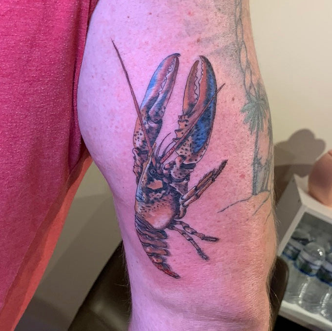 realistic color tattoo of a lobster on the back of an upper arm