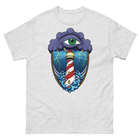 A light grey t-shirt with an old school eye of the storm tattoo design of large dark purple storm clouds at the top of the design with a green eye in the middle of the clouds.  Below the clouds is an oval shape with brown rope. Inside the rope are stormy seas and a lighthouse with lightning striking in the background.  At the bottom of the design, some of the waves are spilling out of the rope barrier. The sky and seas are hues of blue; the lighthouse is white and red striped like a barber pole.