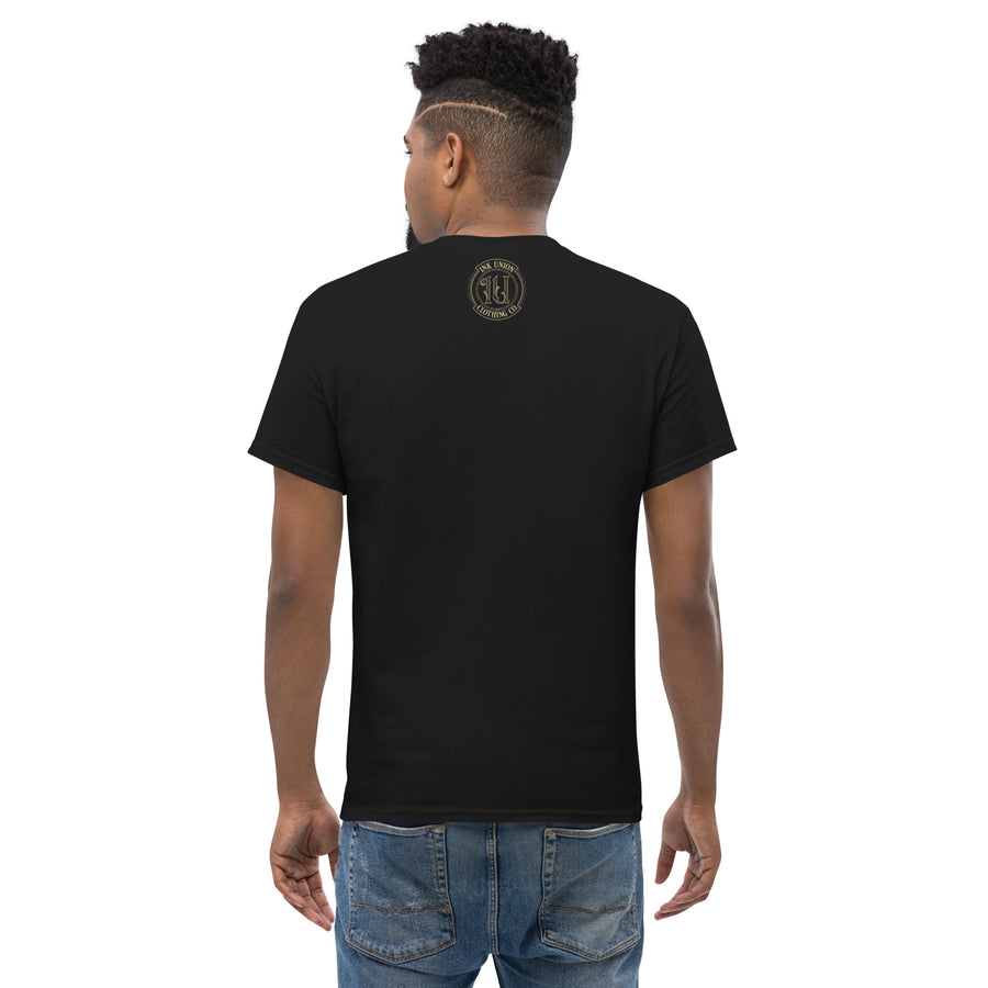 The back view of a man wearing a black t-shirt with a small gold Ink Union Badge Logo centered just under the neckline.