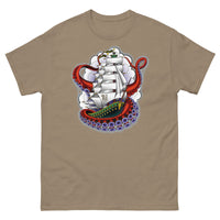 A medium brown t-shirt with an old-school clipper ship tattoo design in green and brown with white sails surrounded by octopus tentacles in shades of red with purple tentacles. Behind the ship are purple-tinged clouds.