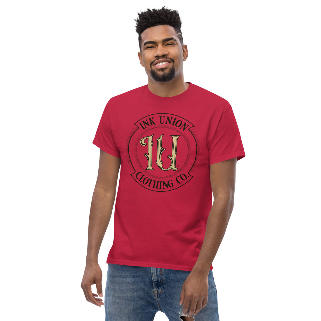 An attractive man is wearing a red t-shirt with the Ink Union Clothing Co Badge logo in black and gold.
