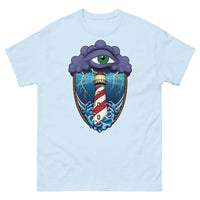 A light blue t-shirt with an old school eye of the storm tattoo design of large dark purple storm clouds at the top of the design with a green eye in the middle of the clouds.  Below the clouds is an oval shape with brown rope. Inside the rope are stormy seas and a lighthouse with lightning striking in the background.  At the bottom of the design, some of the waves are spilling out of the rope barrier. The sky and seas are hues of blue; the lighthouse is white and red striped like a barber pole.