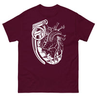 A maroon t-shirt with a white grenade of sold color and line work morphing into an anatomical heart drawn using line work for shading at the top right of the image.