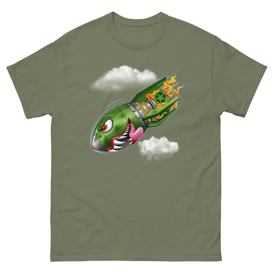 An olive green t-shirt with a military green neo-traditional bomb tattoo design. The bomb is falling with a look of determination in its eyes, an evil toothy grin, and its tongue hanging out of its mouth. Flames are coming from the back of the bomb, and some clouds are in the background.