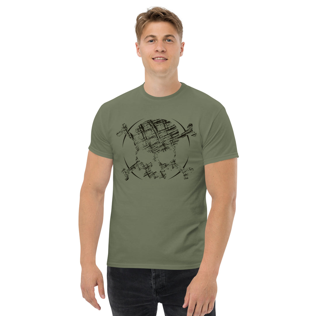 An attractive man is wearing a military green t-shirt adorned with roughly a cross-hatched skull and crossbones in black.  Solid black arcs give the image the impression of movement towards the end of the crossbones.