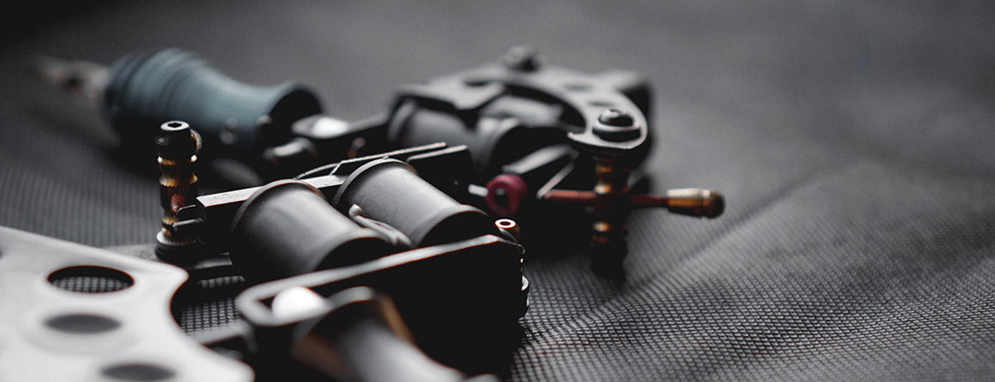 two tattoo machines lying on their side on a piece of cloth