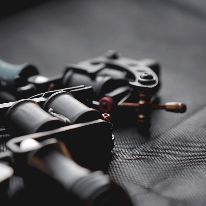 two tattoo machines lying on their side on a piece of cloth