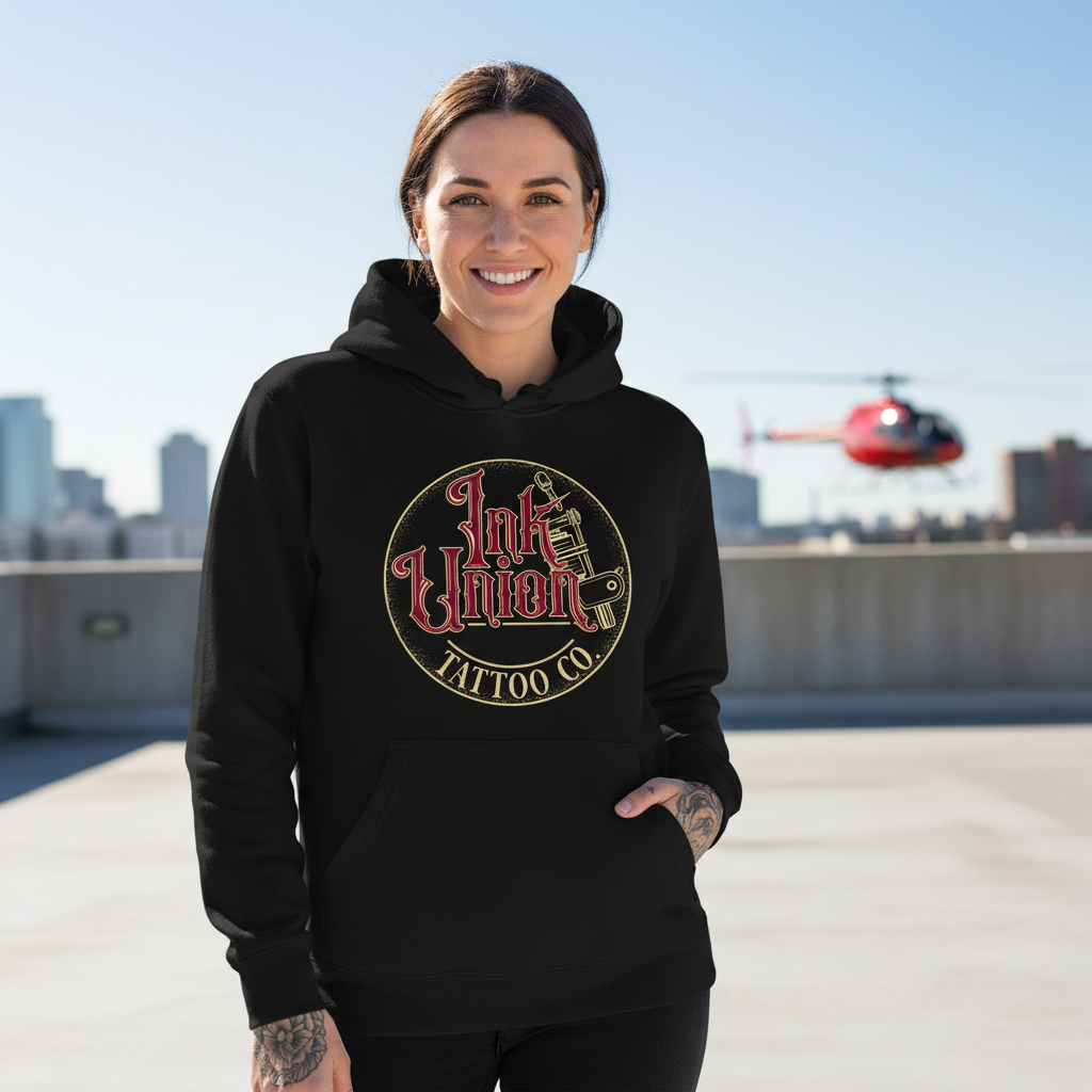 Red & Gold Flash Art Hoodie — Tattooed female model wearing black Ink Union Tattoo Co. red and gold flash art tattoo machine hoodie on rooftop with helicopter in background — alternative streetwear, tattoo artist sweatshirt, unisex heavy blend hoodie, edgy cool fashion


