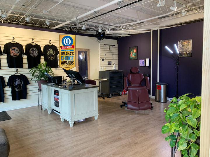 Inside the shop of Ink Union Tattoo Co. A dark red tattoo chair, artwork on the walls, Ink Union T-shirts hanging on the wall, some house plants. It's clean and relaxing. 
Also an Omaha Choice Award winner banner for the tattoo parlor category.