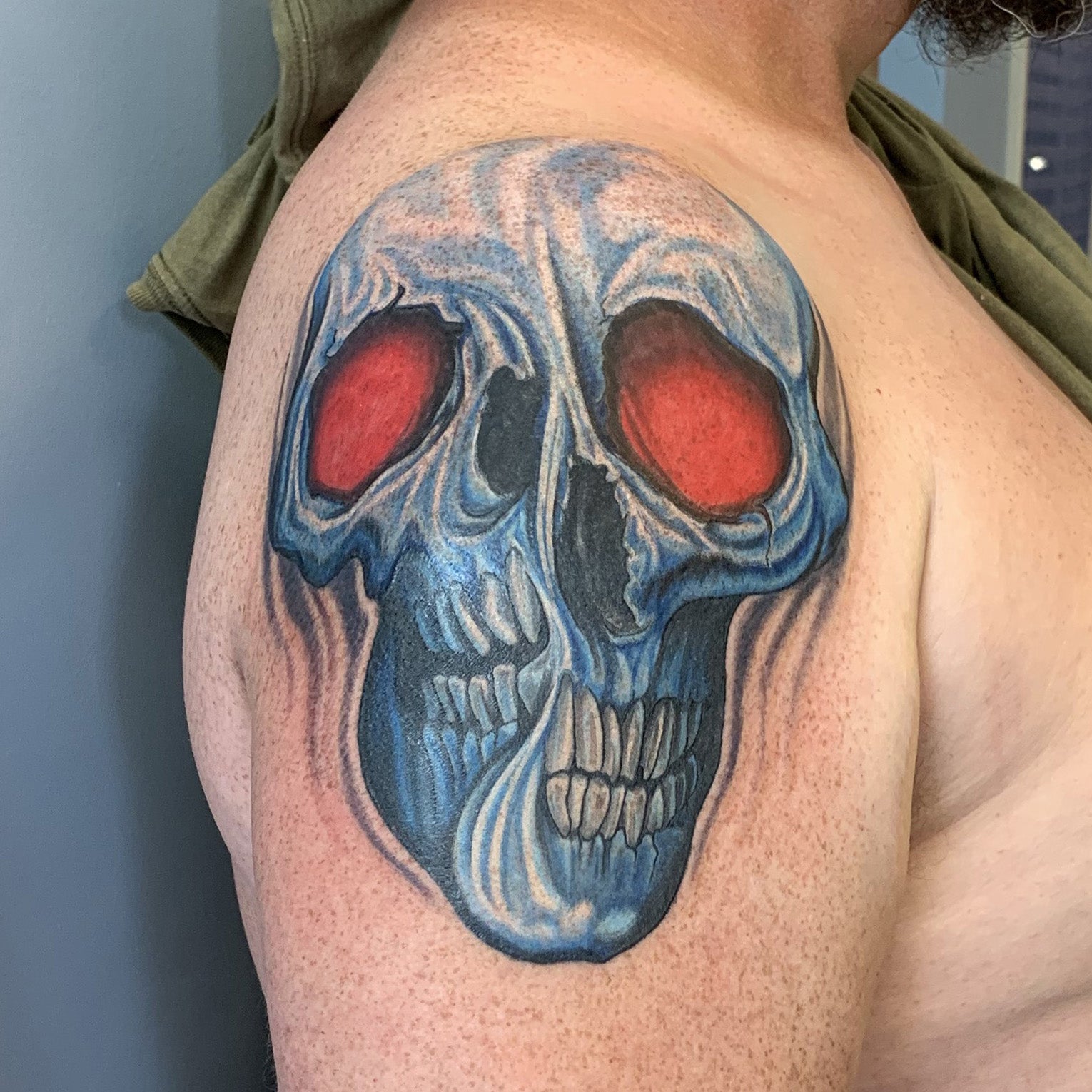 color tattoo coverup of a skull with red eyes being twisted down the middle