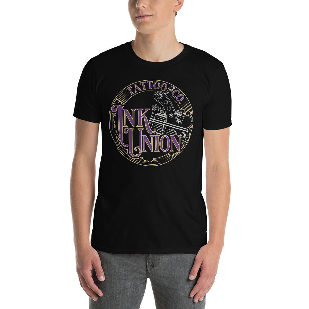 An attractive man wearing a black t-shirt adorned with the Ink Union Tattoo Co. purple and gold with a silver tattoo machine logo.
