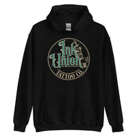 A black hoodie with a gold circle containing fancy lettering in green and gold that says Ink Union and a gold tattoo machine peeking out from behind on the right side.  There is a dot work gradient inside the circle, and the words Tattoo Co. in gold are at the bottom of the design.